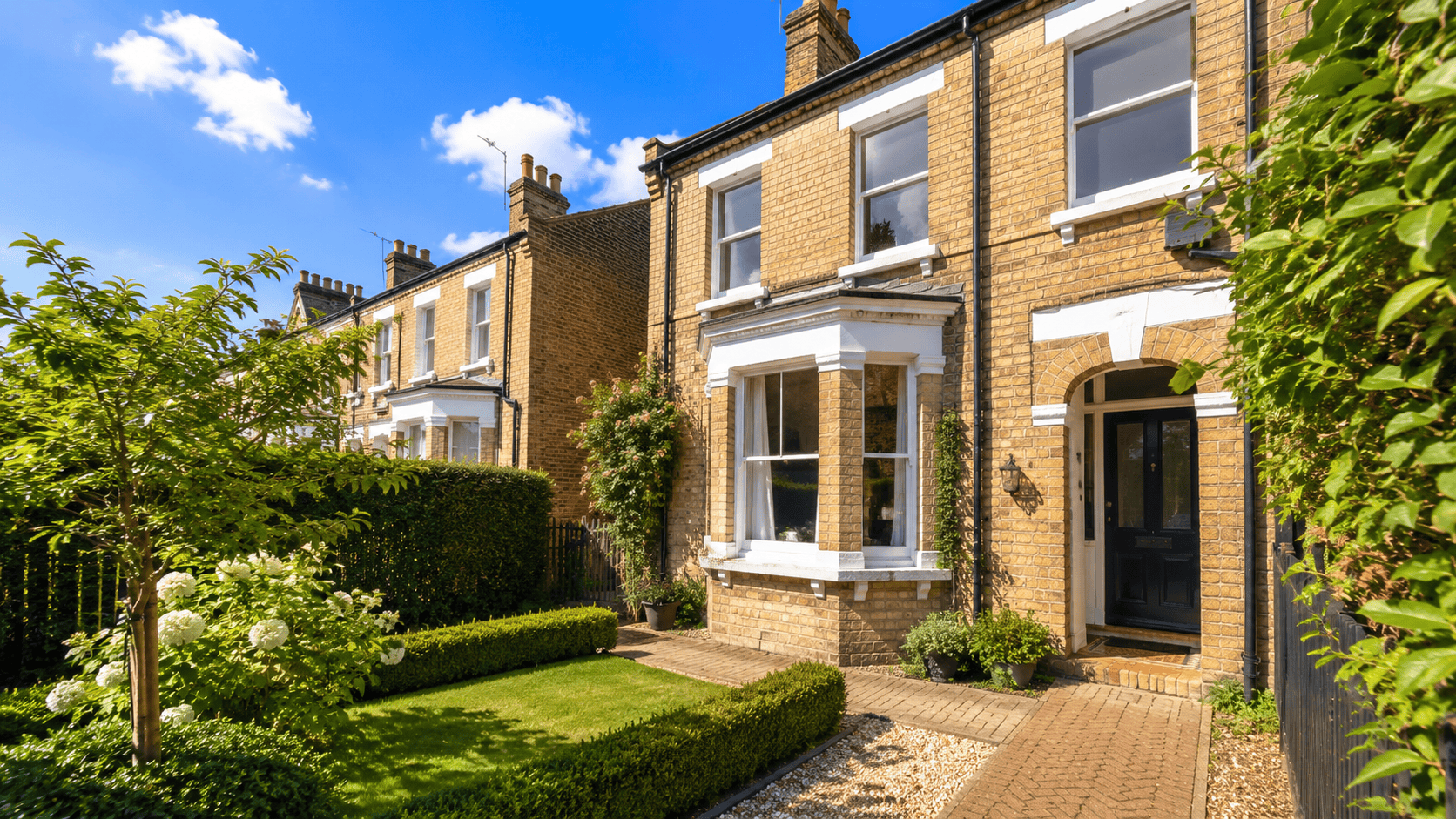 Smart Cambridge brick terraced rental property with a neat front garden on a sunny summer day